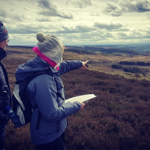 Two people out walking in the countryside, one of them is holding an open map.