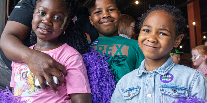 Three children, all holding pompoms, at a Boomchikkaboom family rave.