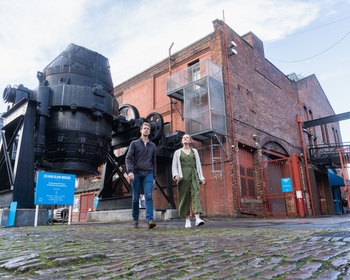 A couple walking in front of the bessemer converter at kelham island museum 