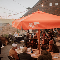 People eating outside at The Mowbray sat under large orange parasols.