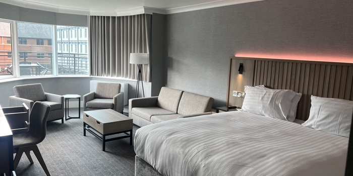 Modern double bedroom with seating area and ambient mood lighting.