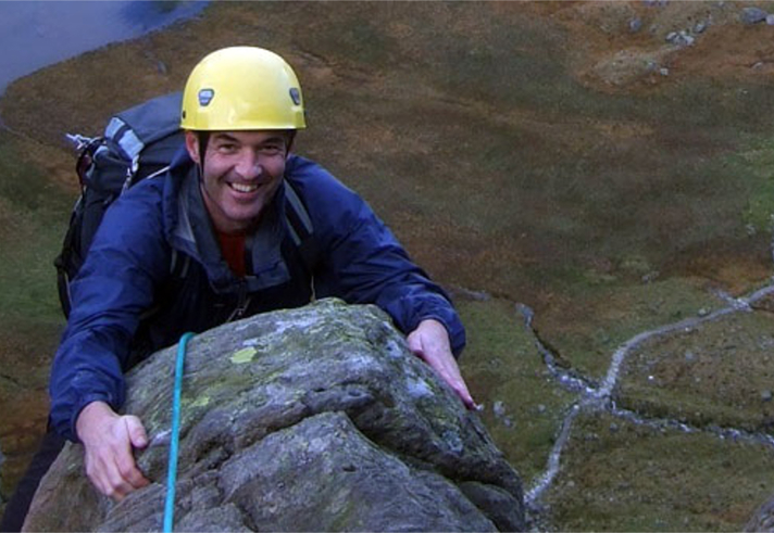 A man smiles as he reaches the top of a climb.