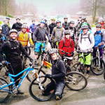 A large group of people on bikes pose for a photo.