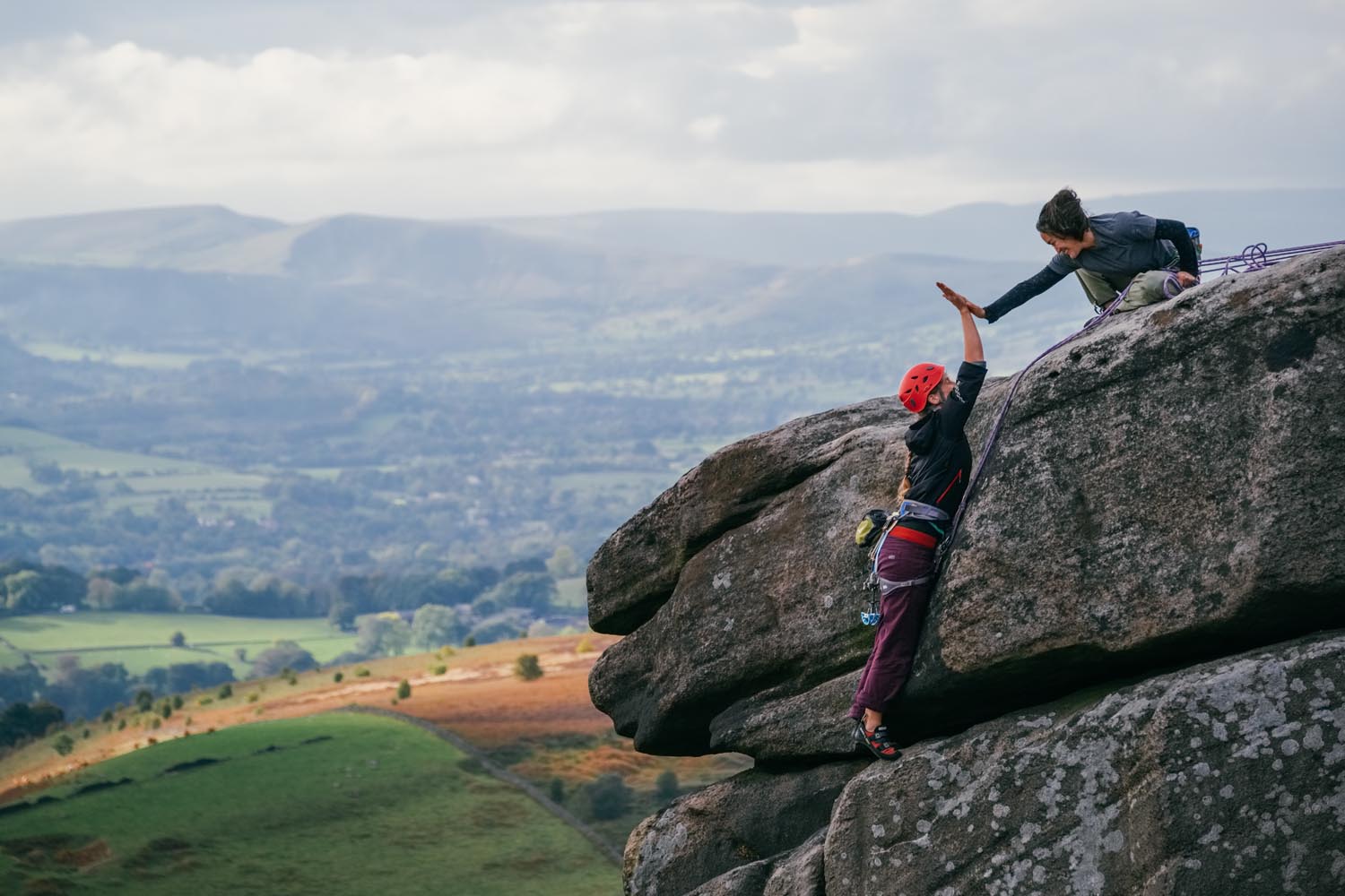 Two climbers on a rocky outcrop high-fiving each other.