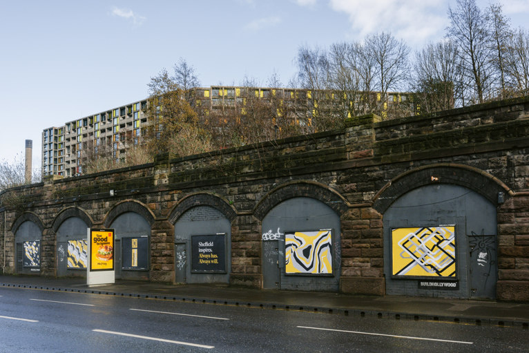 Sheffield's place brand artwork shown poster boards under the arches on Sheaf Street with Park Hill visible above