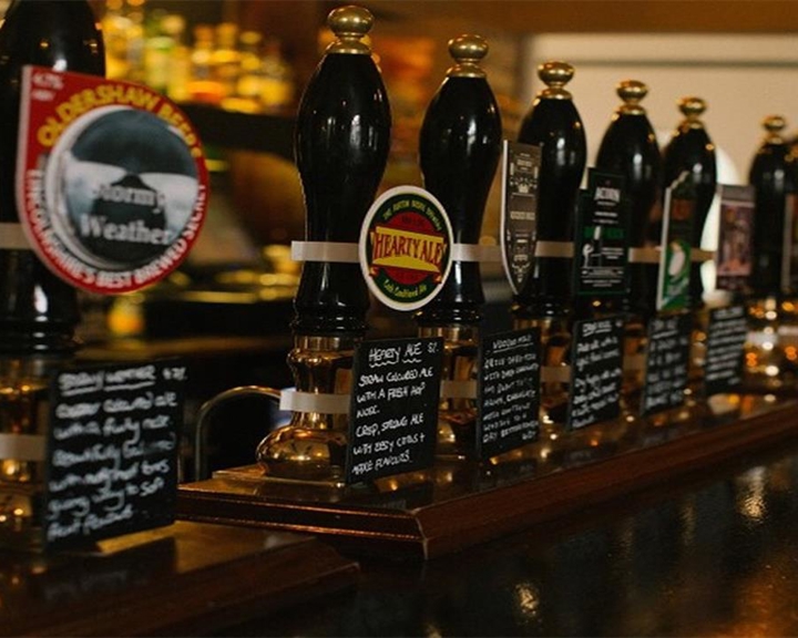 A row of beer taps on a traditional pub bar.