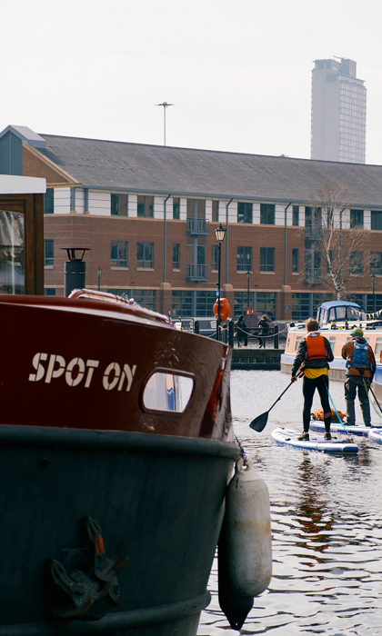 Four people stand up paddle boarding on the canal at Victoria Quays, Sheffield.