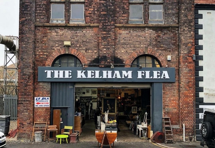 Exterior of an old red brick warehouse, over the open doors is a sign that reads 'The Kelham Flea'.