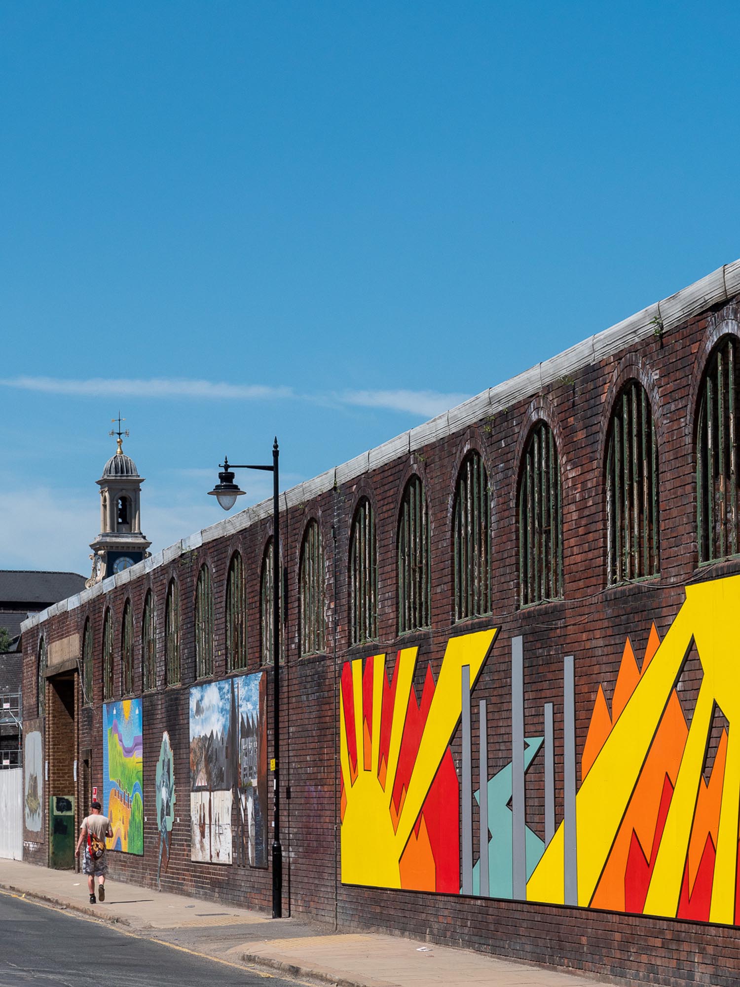 A large brick wall, in Kelham Island, decorated with bright and cheerful street art.