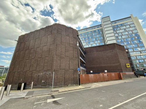 The bare brown brick side of the NCP building exterior on Wellington Street in Sheffield before a mural is painted on it