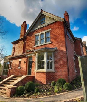 The exterior of Brocco On The Park, a red brick building set in lovely garden.