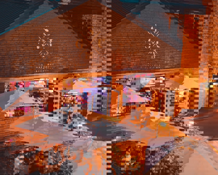 People eating at tables outside Saw Grinders Union at night.