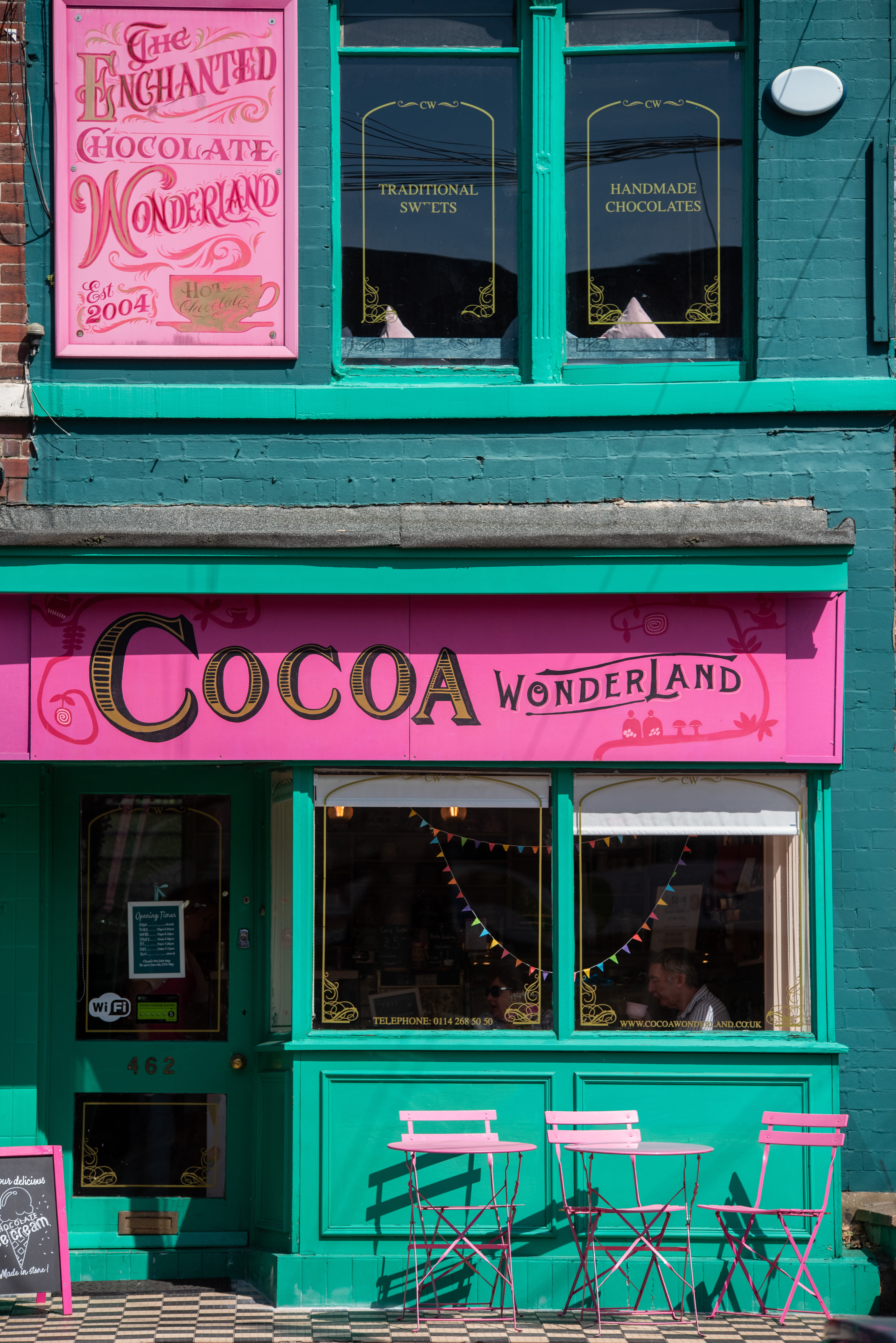 Front view of the Cocoa Wonderland shop with pink and teal signage and a decorated window display.