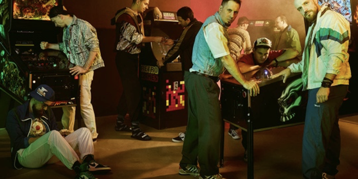 Sumo Digital - 9 men posing around arcade machines.