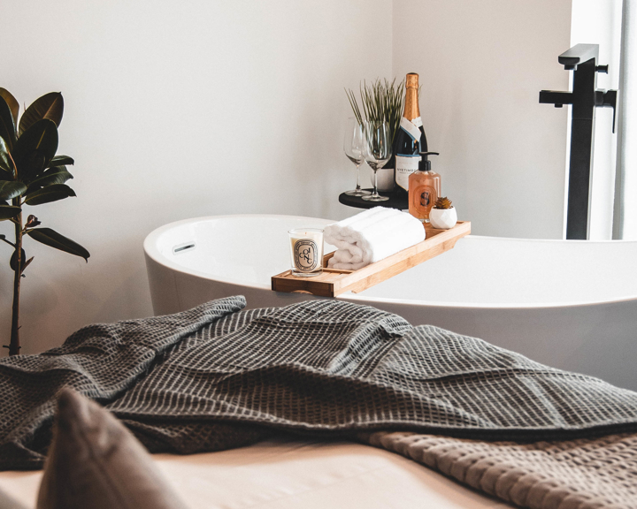 A room at the House Of JÖRO with a double bed in the foreground and a free-standing bath in the background.