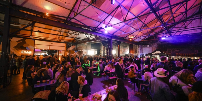 A view inside the Peddler market, there are lots of people seated at tables, eating and chatting.
