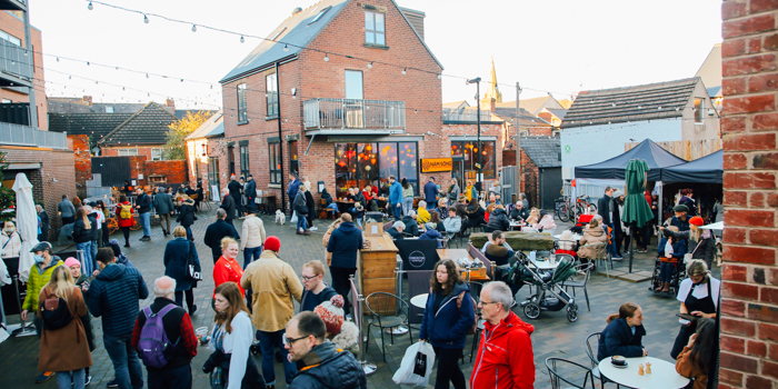 A large crowd of people looking round an outdoor market on Sharrow Vale Road in Sheffield.