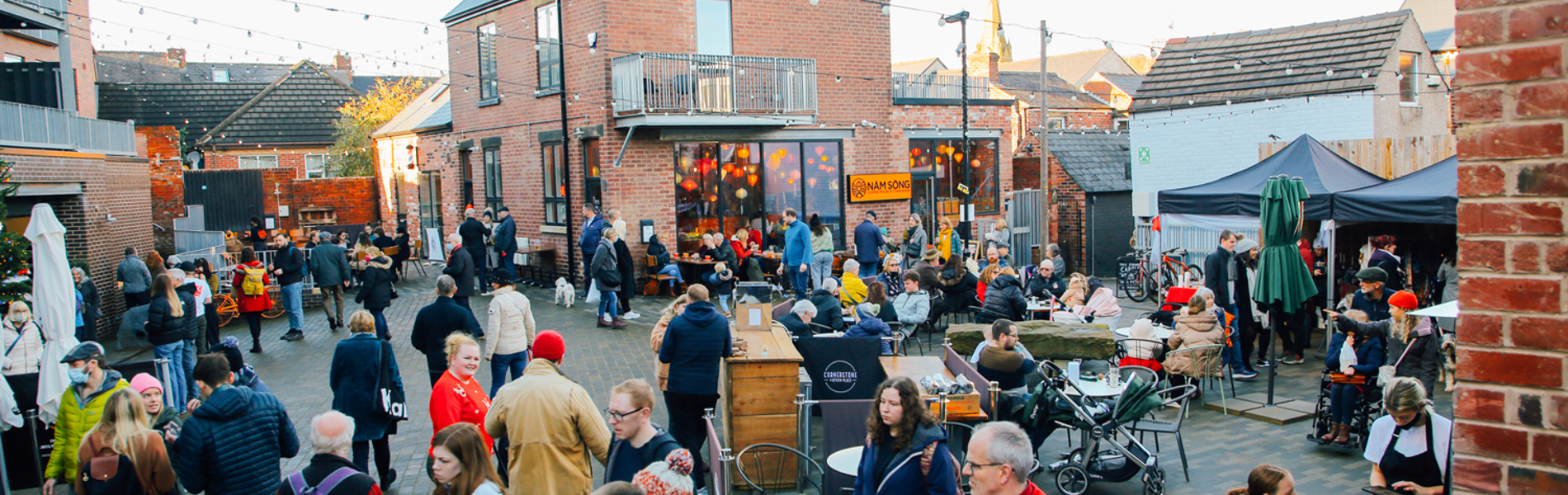 A large crowd of people looking round an outdoor market on Sharrow Vale Road in Sheffield.